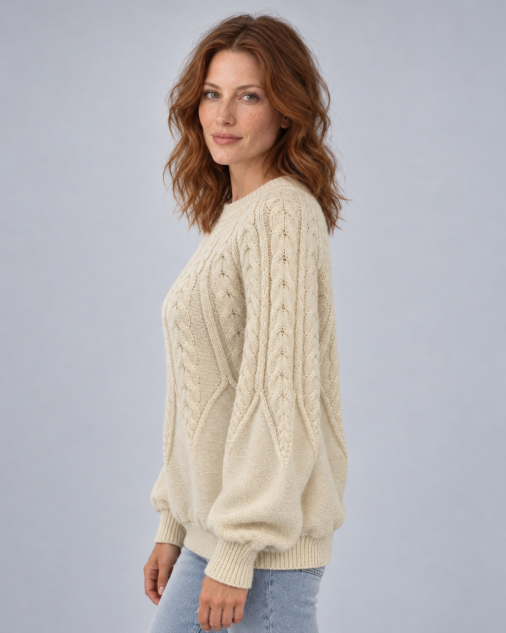 Cream cable-knit crew-neck jumper side angle showing sleeve texture and relaxed fit